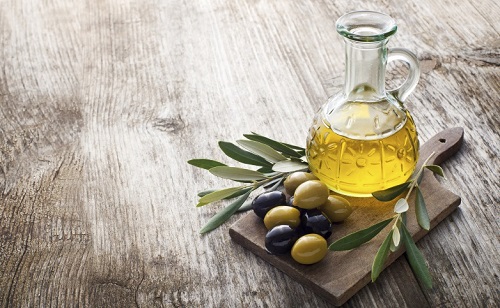 Olive oil and olive branch on the wooden table